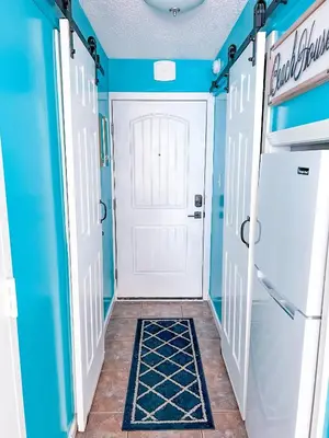 a hallway with a white door and a blue wall at Beachfront Studio - Perfect Location - Free Beach Chairs in Panama City Beach