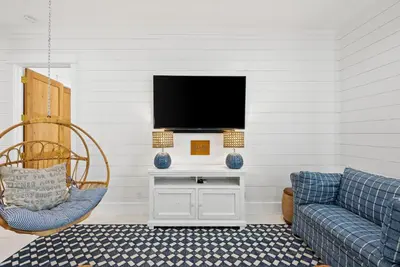 a living room with a couch and a tv on a wall at Salt & Light - 5 BR, Sleeps 18, Gulf & Lake Views, Game Room & Bikes in Seagrove Beach