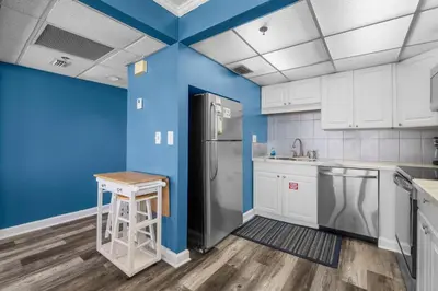 a kitchen with blue walls and a refrigerator at Sunbird Resort! Awe-inspiring Views Throughout! hosted by Dolce Vita Getaways PCB in Panama City Beach