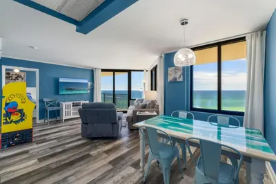 a dining room with a table and chairs and a living room at Sunbird Resort! Awe-inspiring Views Throughout! hosted by Dolce Vita Getaways PCB in Panama City Beach