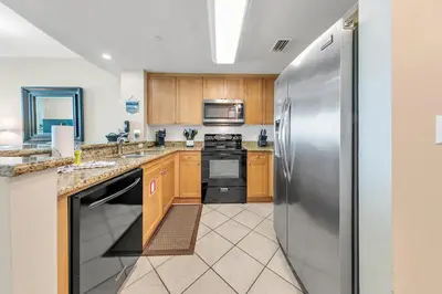 a kitchen with wooden cabinets and stainless steel appliances at Aqua Resort 906 by Emerald Coast Retreats in Panama City Beach
