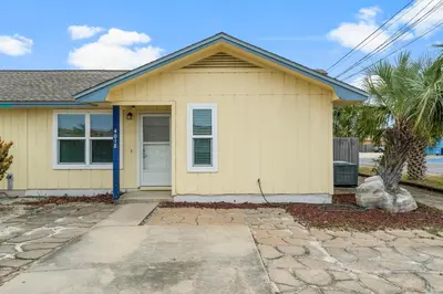 a yellow house with a palm tree in front of it at Beach Hideaway in Panama City Beach