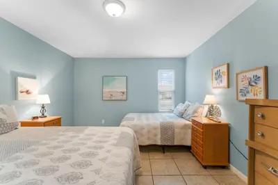 two beds in a bedroom with blue walls at Beach Hideaway in Panama City Beach