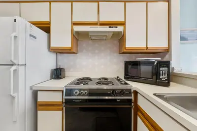 a kitchen with a stove and a microwave at The Inn At St Thomas Square #1305A in Panama City Beach