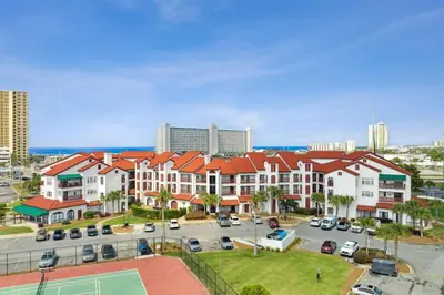 an apartment building with a tennis court in a parking lot at The Inn At St Thomas Square #1305A in Panama City Beach