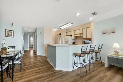 a kitchen and living room with a table and chairs at The Inn At St Thomas Square #1305A in Panama City Beach
