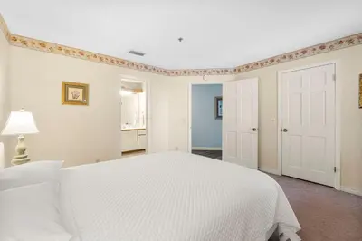 a white bedroom with a white bed and a door at The Inn At St Thomas Square #1305A in Panama City Beach