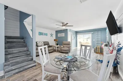 a dining room and living room with a table and chairs at Mimi's Beach Bungalow in Panama City Beach