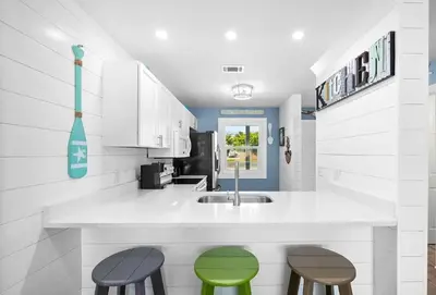a kitchen with two stools and a counter with a sink at Mimi's Beach Bungalow in Panama City Beach