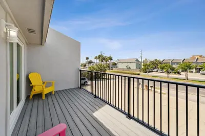 a balcony with a yellow chair and a window at Mimi's Beach Bungalow in Panama City Beach