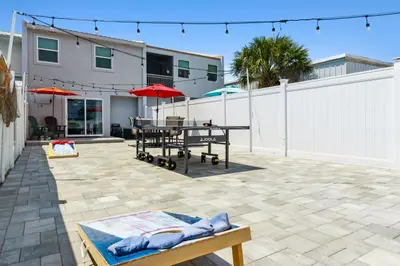 a patio with a table and umbrellas next to a building at Mimi's Beach Bungalow in Panama City Beach