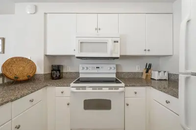 a white kitchen with a stove and a microwave at Shores Of Panama #1509 in Panama City Beach