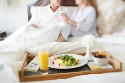 a man and a woman sitting in bed with a plate of food at The Pearl Hotel in Rosemary Beach