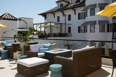 a patio with wicker chairs and tables and a building at The Pearl Hotel in Rosemary Beach