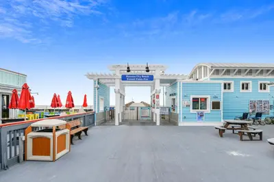 a deck with benches and tables and a blue building at Moonspinner #715A By Book That Condo in Panama City Beach