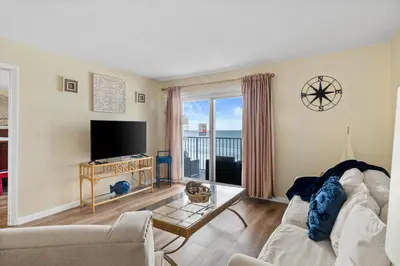 a living room with a couch and a tv at Moonspinner #715A By Book That Condo in Panama City Beach