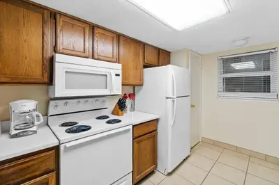 a kitchen with white appliances and wooden cabinets at Moonspinner #715A By Book That Condo in Panama City Beach