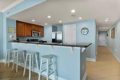 a kitchen with blue walls and bar stools at Palazzo #505 by InJoy Vacations in Panama City Beach