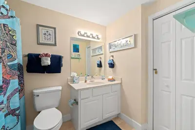 a bathroom with a toilet and a sink and a mirror at Ocean Front Condo 29th Floor - Must be 25 to Book in Panama City Beach