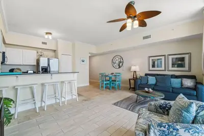 a living room with a blue couch and a kitchen at Ocean Front Condo 29th Floor - Must be 25 to Book in Panama City Beach