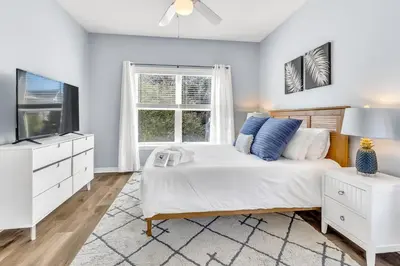 a bedroom with a bed and a tv and a window at Coastside 2 BR with 2BA Sleeps 6 Bikes and Pool View in Santa Rosa Beach