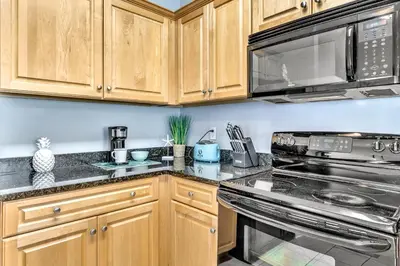 a kitchen with wooden cabinets and stainless steel appliances at Coastside 2 BR with 2BA Sleeps 6 Bikes and Pool View in Santa Rosa Beach