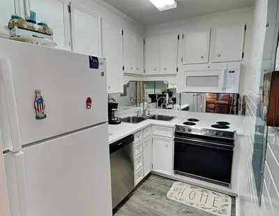 a kitchen with white cabinets and a white refrigerator at Horizon South 83d in Panama City Beach