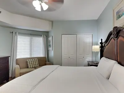 a bedroom with a large white bed and a chair at Shores of Panama #1129 in Panama City Beach