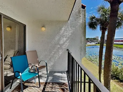 a blue chair sitting on a porch with palm trees at Edgewater Villa #121 in Panama City Beach