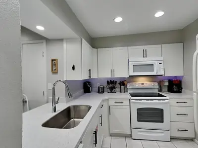 a white kitchen with a sink and a microwave at Edgewater Villa #121 in Panama City Beach