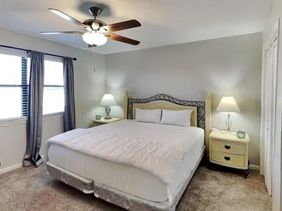 a bedroom with a white bed and a ceiling fan at Edgewater Villa #121 in Panama City Beach