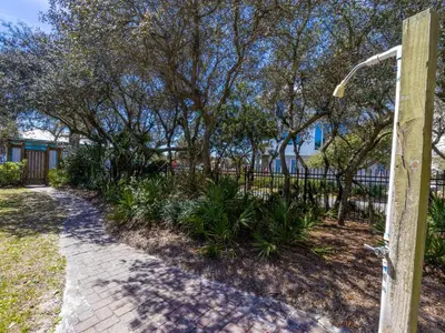 a fence with trees and a walkway at Inlet Dunes #102 in Inlet Beach