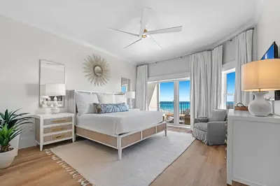 a white bedroom with a bed and a chair at The Legacy Unit 203 in Seagrove Beach
