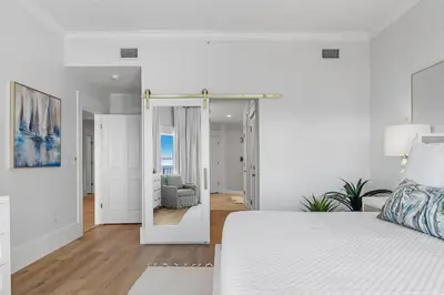a white bedroom with a bed and a living room at The Legacy Unit 203 in Seagrove Beach