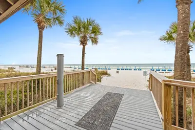 a wooden walkway to the beach with palm trees at Summerhouse Beach Resort by Panhandle Getaways in Panama City Beach
