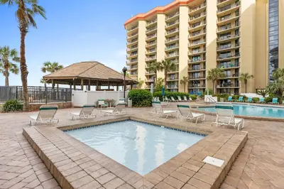a swimming pool with chairs and a large building at Summerhouse Beach Resort by Panhandle Getaways in Panama City Beach