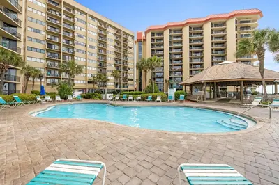 a swimming pool with two lounge chairs and a large building at Summerhouse Beach Resort by Panhandle Getaways in Panama City Beach