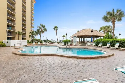 a swimming pool at a resort with chairs and palm trees at Summerhouse Beach Resort by Panhandle Getaways in Panama City Beach