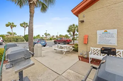 a building with a grill and a parking lot with palm trees at Summerhouse Beach Resort by Panhandle Getaways in Panama City Beach