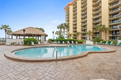 a swimming pool with chairs and a building at Summerhouse Beach Resort by Panhandle Getaways in Panama City Beach