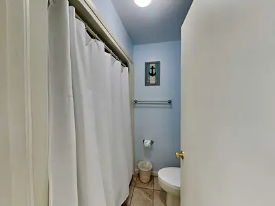 a bathroom with a toilet and a white shower curtain at Edgewater Villa #1607 in Panama City Beach