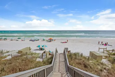 a boardwalk to the beach with people on the beach at Beach House with Heated Pool 100 Steps from Beach in Panama City Beach