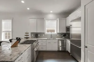 a kitchen with white cabinets and stainless steel appliances at Beach House with Heated Pool 100 Steps from Beach in Panama City Beach