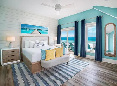 a bedroom with a bed and a chair and windows at Margaritaville Beach Cottage Resort Panama City Beach in Panama City Beach