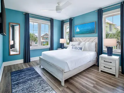 a blue bedroom with a bed and two windows at Margaritaville Beach Cottage Resort Panama City Beach in Panama City Beach