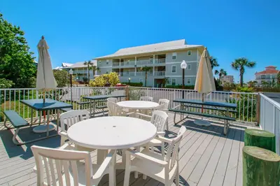 a deck with tables and chairs and umbrellas at Beachside Villas 814 in Santa Rosa Beach