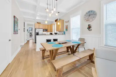 a dining room and kitchen with a table and benches at Claire N' Bea by the Sea in Santa Rosa Beach