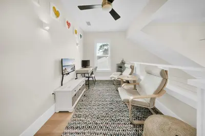 a living room with a staircase with chairs and a desk at Claire N' Bea by the Sea in Santa Rosa Beach