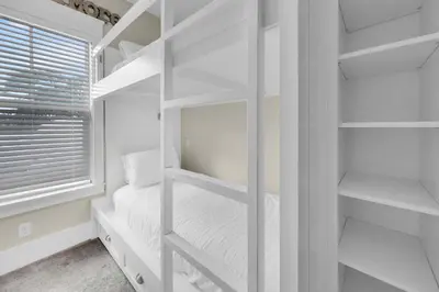 a white bedroom with white shelves and a window at Claire N' Bea by the Sea in Santa Rosa Beach