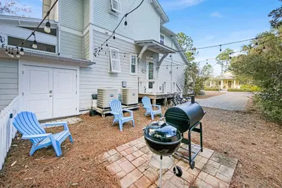 a backyard with a grill and chairs and a house at Claire N' Bea by the Sea in Santa Rosa Beach
